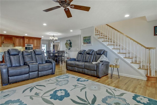 living room with light hardwood / wood-style floors and ceiling fan with notable chandelier