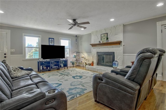 living room featuring ornamental molding, a stone fireplace, and light wood-type flooring