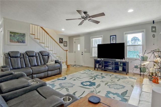 living room featuring light wood-type flooring, a textured ceiling, and ceiling fan