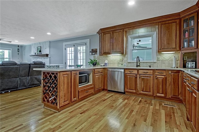 kitchen featuring appliances with stainless steel finishes, light hardwood / wood-style floors, sink, backsplash, and kitchen peninsula