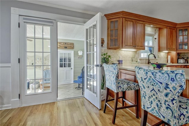 kitchen featuring crown molding, light wood-type flooring, decorative backsplash, and sink