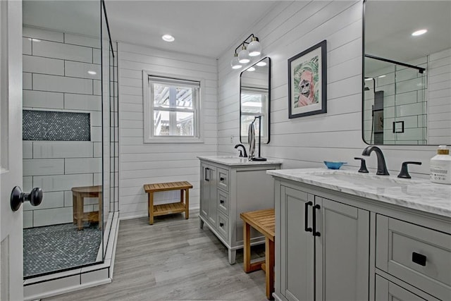 bathroom featuring hardwood / wood-style flooring, a shower with shower door, wood walls, and vanity