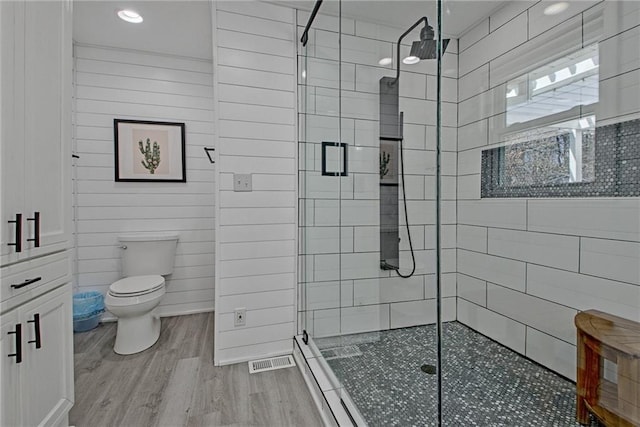 bathroom featuring toilet, wood walls, hardwood / wood-style floors, and an enclosed shower