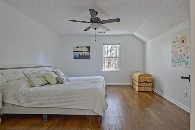 bedroom featuring hardwood / wood-style floors, a textured ceiling, vaulted ceiling, and ceiling fan