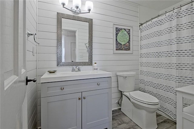 bathroom featuring wood-type flooring, vanity, toilet, wood walls, and a shower with shower curtain