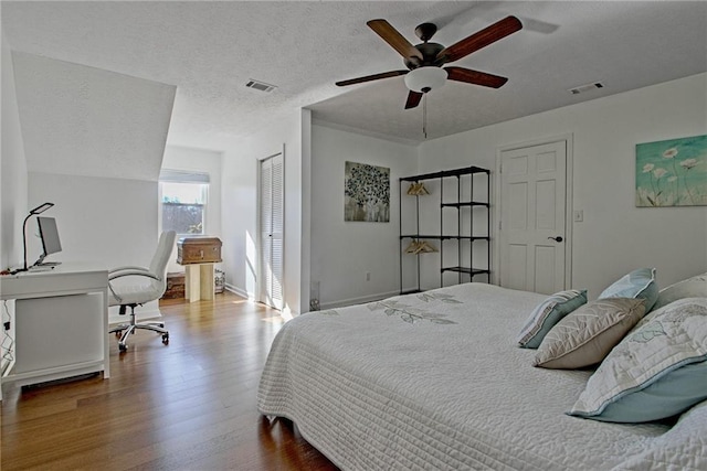 bedroom featuring ceiling fan, wood-type flooring, and a textured ceiling