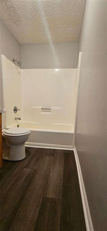 full bathroom featuring vanity, washtub / shower combination, hardwood / wood-style flooring, toilet, and a textured ceiling