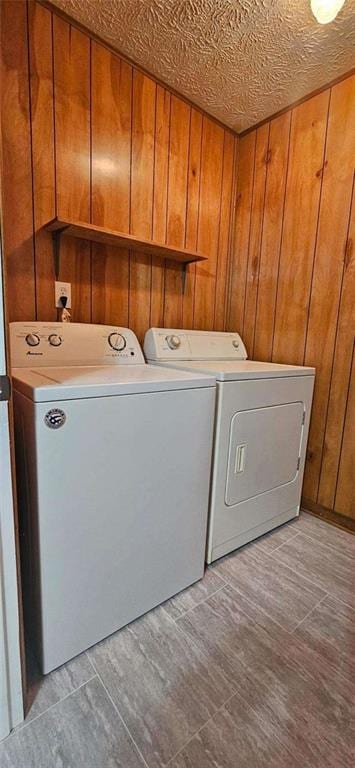 clothes washing area featuring wooden walls and washing machine and clothes dryer