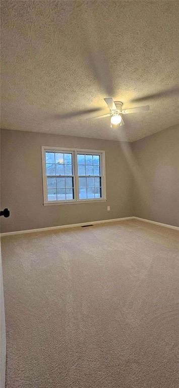 unfurnished room with lofted ceiling, ceiling fan, carpet, and a textured ceiling