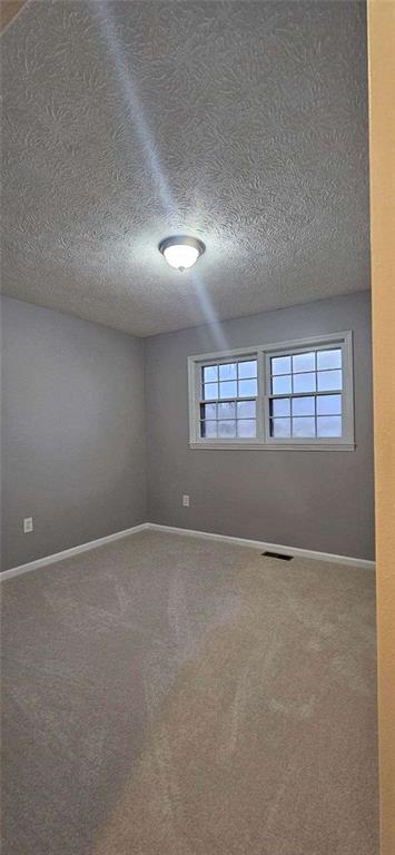 empty room with carpet and a textured ceiling