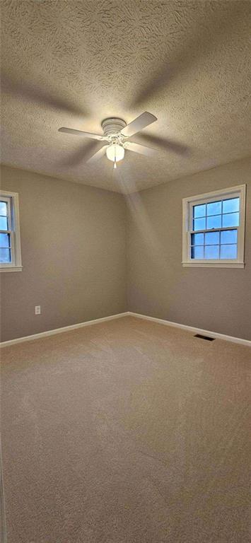 carpeted empty room featuring a textured ceiling and ceiling fan