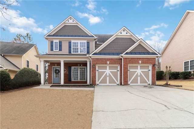 view of front facade with driveway, an attached garage, a standing seam roof, covered porch, and brick siding