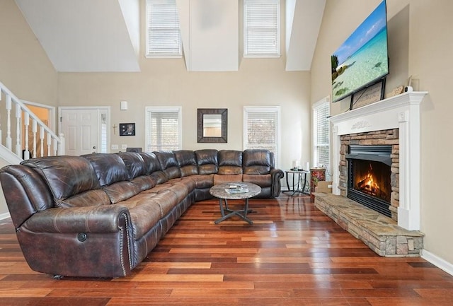 living room featuring hardwood / wood-style floors, a stone fireplace, and high vaulted ceiling