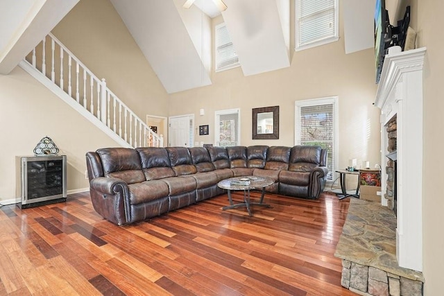 living room featuring hardwood / wood-style floors, a stone fireplace, and a high ceiling