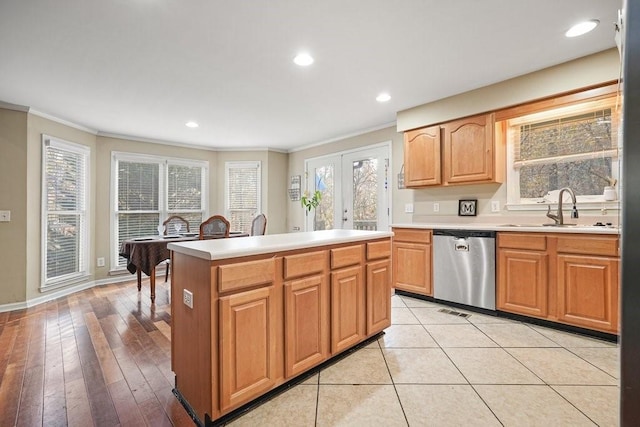 kitchen featuring a center island, crown molding, sink, light hardwood / wood-style flooring, and stainless steel dishwasher