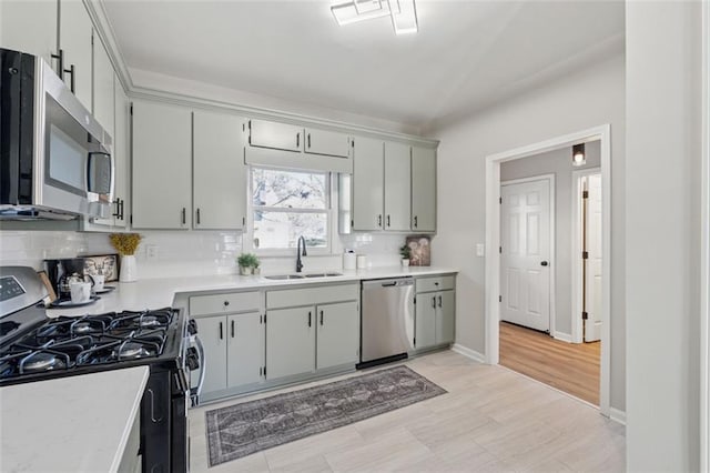 kitchen featuring tasteful backsplash, appliances with stainless steel finishes, light countertops, and a sink