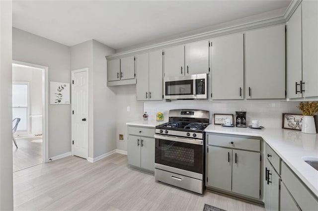 kitchen featuring light countertops, appliances with stainless steel finishes, decorative backsplash, and gray cabinetry