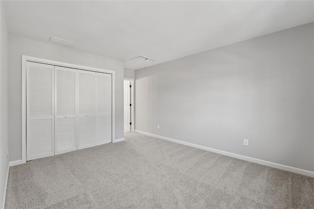 unfurnished bedroom featuring attic access, a closet, carpet floors, and baseboards