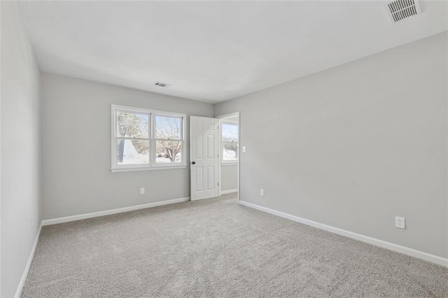 spare room with carpet floors, visible vents, and baseboards