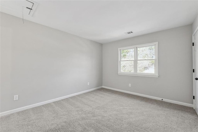 empty room with attic access, visible vents, carpet floors, and baseboards