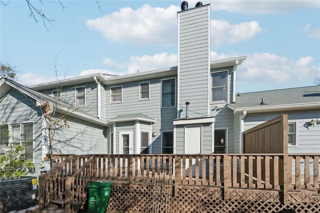 back of house with a chimney, central AC unit, and a deck