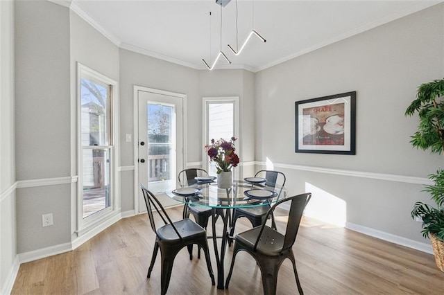 dining space with a wealth of natural light, crown molding, light wood-style flooring, and baseboards