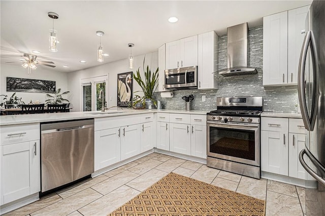 kitchen featuring decorative backsplash, wall chimney exhaust hood, stainless steel appliances, pendant lighting, and white cabinetry