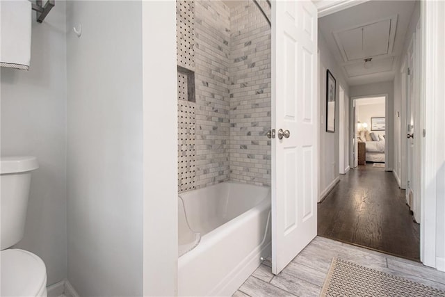 bathroom featuring hardwood / wood-style flooring, toilet, and tiled shower / bath