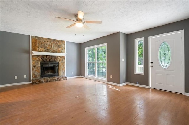 unfurnished living room with a fireplace, a textured ceiling, light wood-type flooring, and ceiling fan