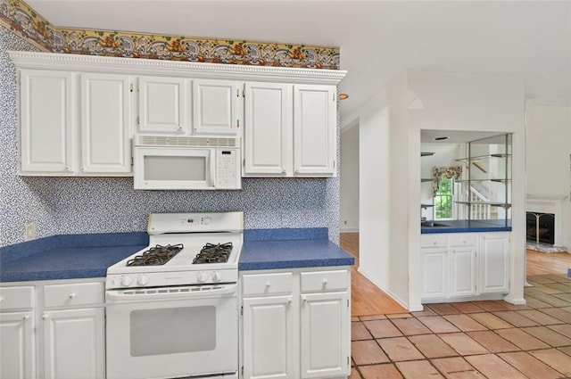2866 Wynford Dr SW, Marietta, GA 30064 - kitchen with white appliances, light tile patterned floors, white cabinetry, dark countertops, and decorative backsplash