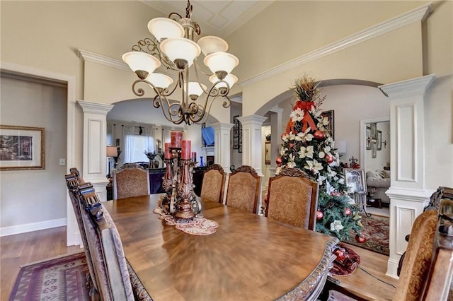 dining room featuring dark hardwood / wood-style flooring, decorative columns, crown molding, and a notable chandelier