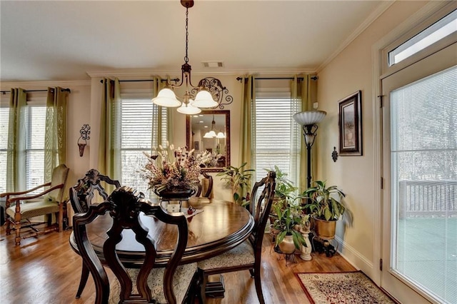 dining room with crown molding, hardwood / wood-style floors, and a notable chandelier