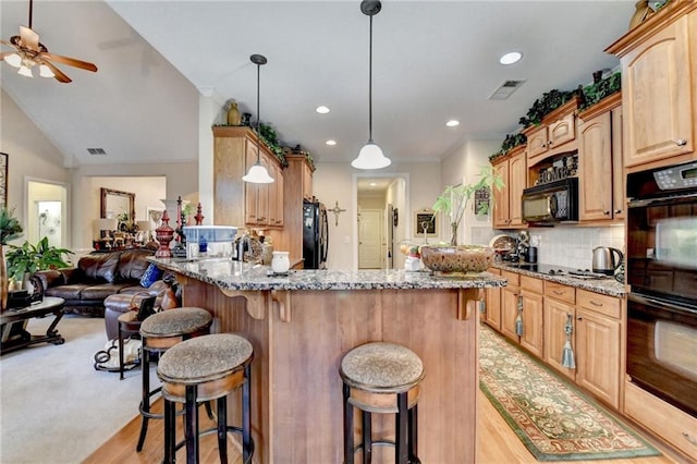 kitchen with black appliances, light stone countertops, light hardwood / wood-style floors, and decorative light fixtures