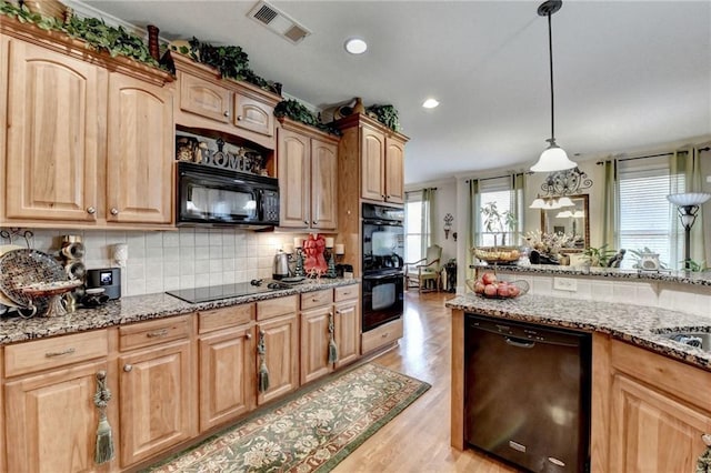 kitchen with black appliances, decorative light fixtures, light stone counters, and light hardwood / wood-style flooring