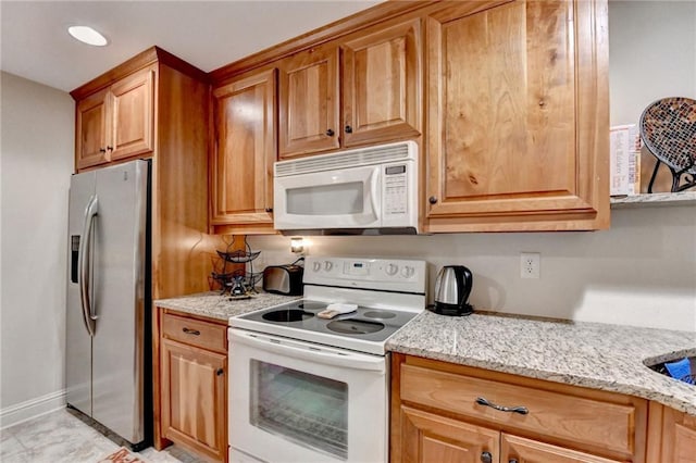 kitchen with light stone countertops and white appliances