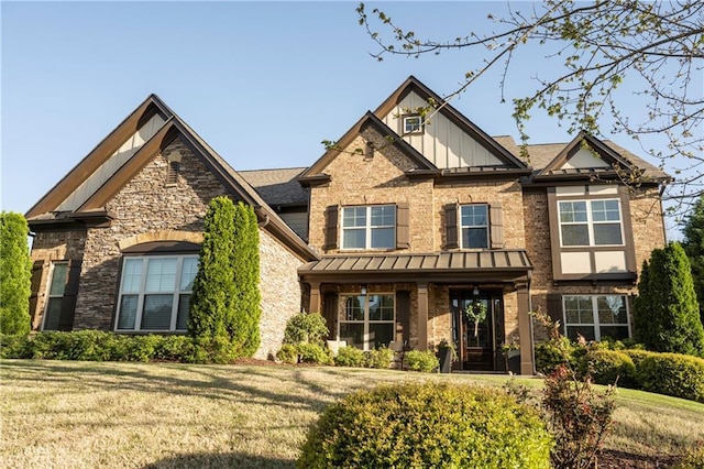 craftsman-style home featuring board and batten siding, a standing seam roof, brick siding, a front lawn, and stone siding