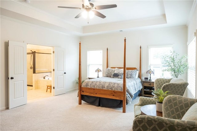 bedroom with ensuite bathroom, ornamental molding, a raised ceiling, and light carpet