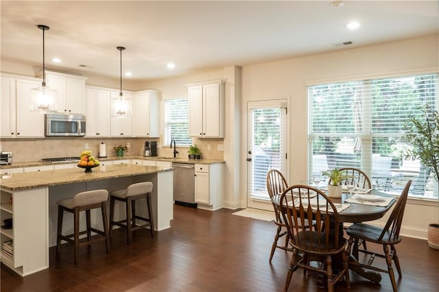 kitchen with a sink, a center island, stainless steel appliances, decorative backsplash, and visible vents