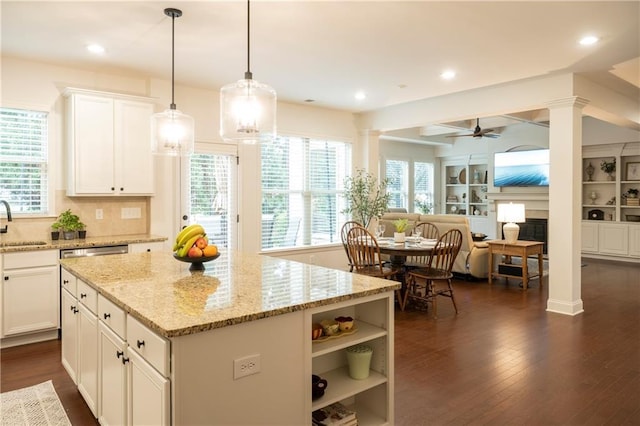kitchen featuring a ceiling fan, decorative columns, a sink, open floor plan, and white cabinetry