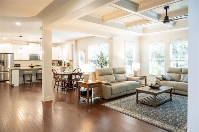 living room with plenty of natural light, ornamental molding, a ceiling fan, and beamed ceiling
