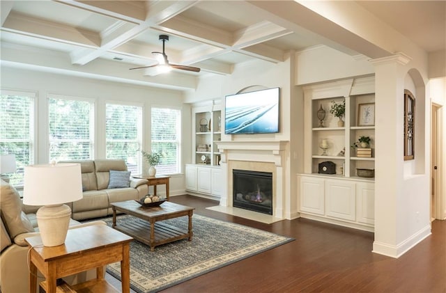 living room featuring a ceiling fan, baseboards, a high end fireplace, beamed ceiling, and dark wood-type flooring