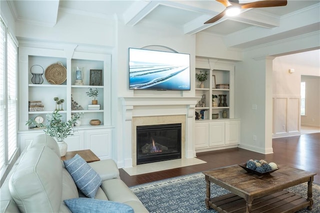 living area with ornamental molding, built in features, dark wood-style floors, a ceiling fan, and a premium fireplace