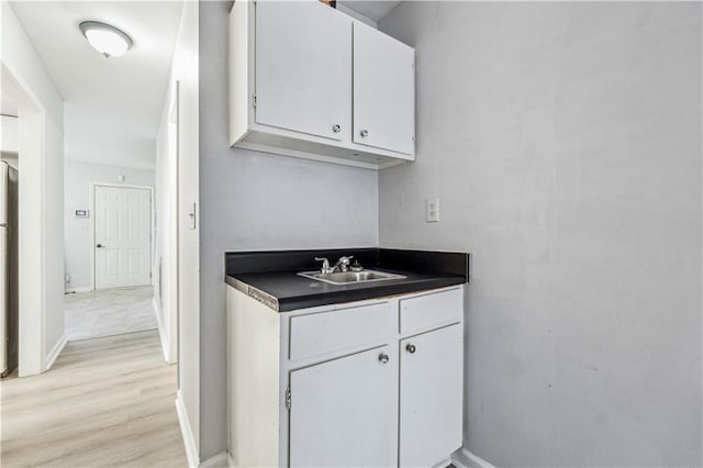 kitchen featuring white cabinets, stainless steel fridge, light hardwood / wood-style flooring, and sink