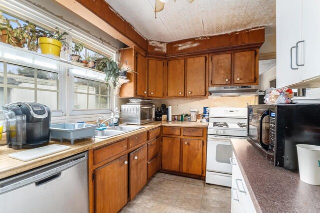 kitchen with under cabinet range hood, an ornate ceiling, stainless steel appliances, and brown cabinetry