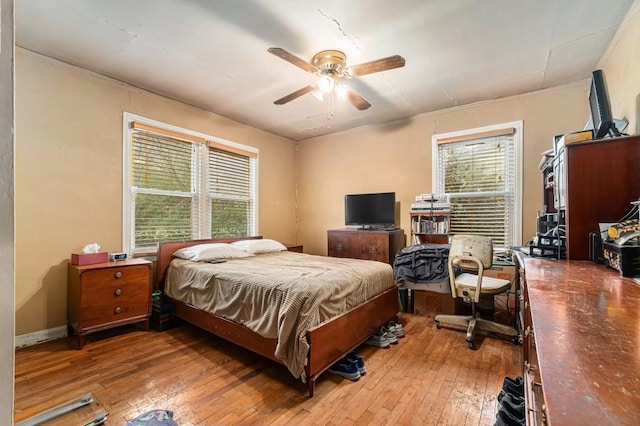 bedroom featuring a ceiling fan, multiple windows, and light wood finished floors