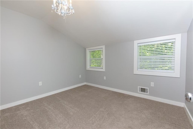 carpeted spare room featuring a notable chandelier and lofted ceiling