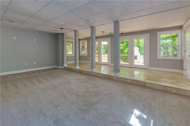 unfurnished room with a paneled ceiling, plenty of natural light, light colored carpet, and french doors