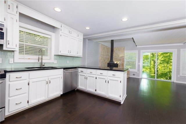 kitchen with white cabinetry, a wood stove, sink, and appliances with stainless steel finishes