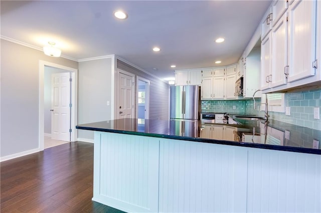 kitchen with stainless steel appliances, dark hardwood / wood-style floors, kitchen peninsula, white cabinets, and ornamental molding