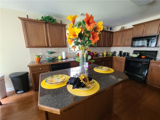 kitchen with tasteful backsplash, dark countertops, visible vents, and black appliances